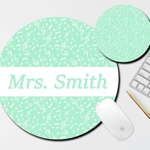 May include: A round, light green mousepad with a white border and the text "Mrs. Smith" in the center. The mousepad is covered in a pattern of white musical notes.