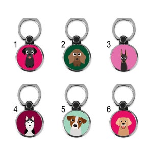 May include: Six phone ring holders with different dog breeds on them. The rings are silver and the backgrounds are pink, green, and burgundy.