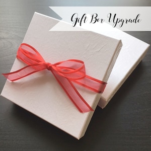 May include: White gift box with a red ribbon tied around it. The box is labeled "Gift Box Upgrade".