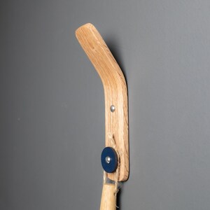 An oak wood wall hook featuring a stylish navy blue leather accent, adding an elegant touch to any room's décor