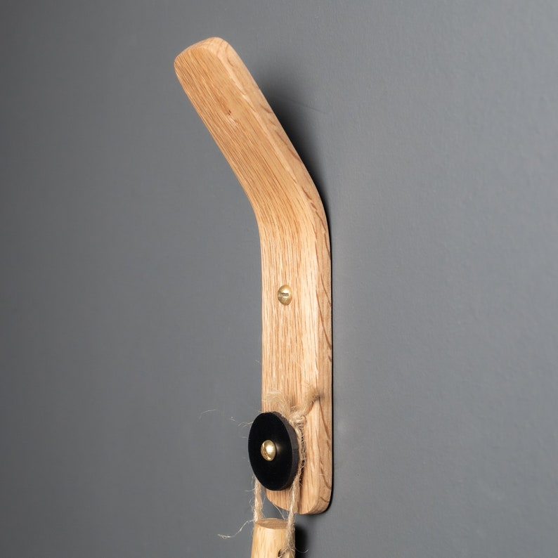 A sophisticated oak wood wall hook with a black leather accent, ideal for arranging clothes hangers, scarves, and accessories, creating a charming closet organization solution