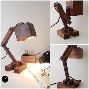 K&ouml;nnte beinhalten: Eine Schreibtischlampe aus Holz mit einem braunen Holzschirm und einem schwarzen Kabel. Die Lampe ist verstellbar und hat ein einzigartiges Design.