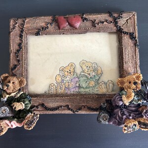 May include: A decorative picture frame with a brown wooden frame, featuring two teddy bears on the sides holding telephones. The frame has a picture of two teddy bears on the inside. Two red hearts are at the top.