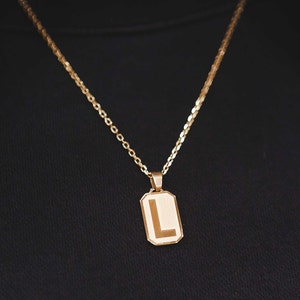 May include: A gold chain necklace with a pendant featuring the letter L.