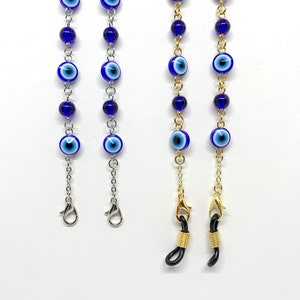 May include: A collection of four beaded eyeglass chains. Two chains are silver-toned with blue and white evil eye beads and dark blue beads. The other two chains are gold-toned with similar beads and black eyeglass holders.