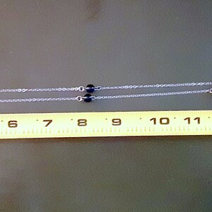 May include: A silver chain eyeglass holder with blue and black beads. The eyeglass holder is approximately 43 cm long.