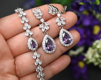 May include: A set of purple teardrop earrings with clear crystal accents and a matching bracelet. The earrings are clip-on style for non-pierced ears. #24 purple