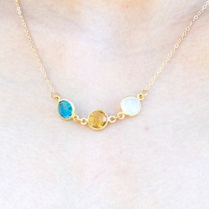 May include: A gold chain necklace with three round gemstones: a blue gemstone, a yellow gemstone, and a white gemstone.