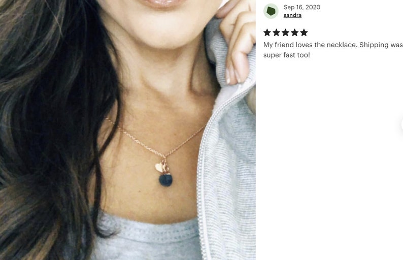 May include: A gold chain necklace with a small heart charm and a larger black lava stone pendant.