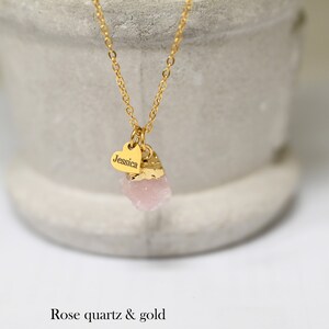 May include: A gold chain necklace with a small heart charm engraved with the name "Jessica" and a pink rose quartz pendant.
