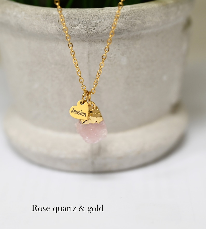 May include: A gold chain necklace with a small heart charm engraved with the name "Jessica" and a pink rose quartz pendant.