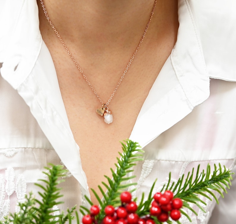 May include: A delicate rose gold necklace with a small heart charm and a white crystal pendant.