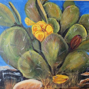 Puede incluir: Una pintura al &oacute;leo sobre lienzo que representa un cactus de nopal con paletas verdes, espinas blancas, una flor amarilla vibrante en plena floraci&oacute;n y un peque&ntilde;o fruto marr&oacute;n rojizo, sobre un cielo azul y terreno rocoso.