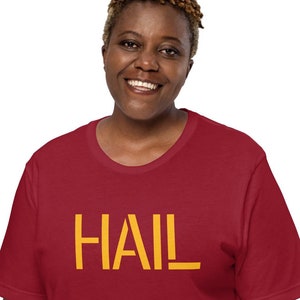 May include: A red t-shirt with the word "HAIL" printed in yellow on the front.