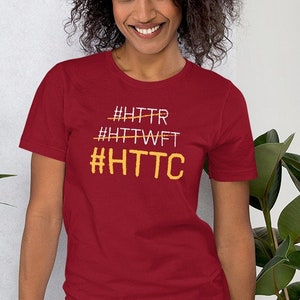 Könnte beinhalten: Ein rotes T-Shirt mit kurzen Ärmeln und einem weißen und gelben Grafikdruck mit der Aufschrift "#HTTR #HTTWT #HTTC".