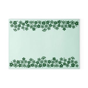 May include: A light green background with a border of dark green stylized flowers. The flowers are arranged in a row at the top and bottom of the image.