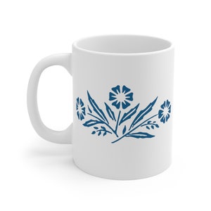 May include: White ceramic mug with a blue floral design. The design features three stylised flowers with leaves.
