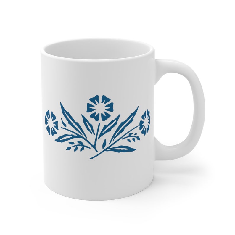 May include: White ceramic mug with a blue floral design. The design features three stylised flowers with leaves.