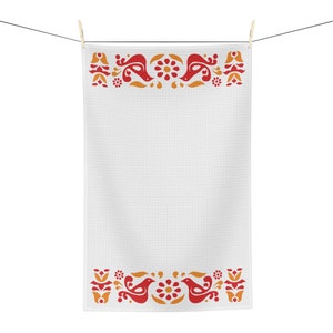 May include: White kitchen towel with a red and orange folk art design of birds and flowers. The towel is hanging on a clothesline.