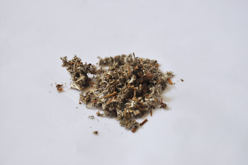 May include: A pile of dried, shredded plant material, with a mix of brown, gray, and white hues. The texture appears fibrous and slightly coarse, suggesting it may be used for herbal remedies or crafts. The background is plain white.