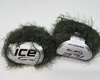 May include: Two balls of dark green yarn with a fuzzy texture. Each ball has a silver label with the brand name "ICE YARNS" printed in black. The yarn appears soft and suitable for knitting or crochet projects.
