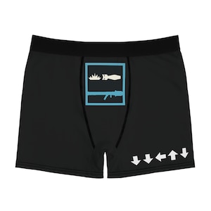 May include: Black boxer briefs featuring a central light blue square graphic containing a white explosion icon, a white bomb icon, and a light blue rifle silhouette. The lower right corner displays a sequence of five white directional arrows.