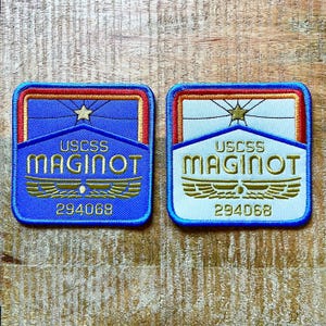 以下が含まれることがあります： USCSS MAGINOT 294068という文字が刺繍された2枚の正方形のワッペン。1枚は青い背景、もう1枚は白い背景です。どちらも金色の星、金色の翼、そして青い縁取りの赤とオレンジのボーダーが特徴です。