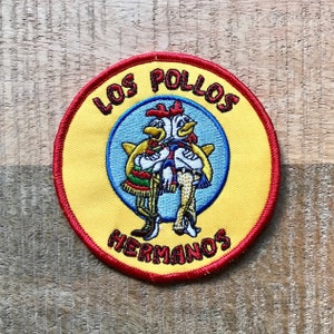Könnte beinhalten: Ein gestickter Aufnäher in Gelb und Rot mit dem Text "Los Pollos Hermanos" und einem Cartoon-Bild von zwei Hühnern, die Sombreros tragen.