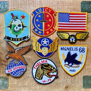 Puede incluir: Una colección de diez parches bordados con varios diseños, incluyendo una calavera, un pájaro, una serpiente, un avión y una estrella. Los parches son todos de diferentes colores y tienen diferentes textos en ellos, incluyendo "Risky", "Air Division", "Lucky", "Thelma", "Menelis 68" y "VF-72".
