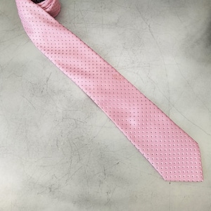 May include: A pink tie with a white polka dot pattern.