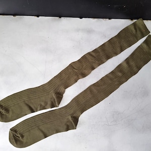 May include: A pair of olive green knee-high socks with a ribbed texture.