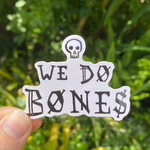 May include: White sticker with black text that reads "We Do Bones" with a skull graphic above the text.