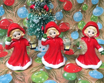 Vintage Ceramic Christmas Figurines Giftcraft Napco Girls in red hooded cloaks with bottle brush wreath and lanterns