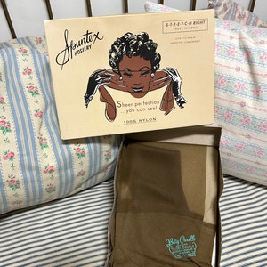 May include: A vintage Spuntex Hosiery box featuring a retro illustration of a woman. The box is beige with black text and a drawing of a woman wearing gloves. Inside the box are sheer nylon stockings. The text on the box reads "Sheer perfection...you can see!"