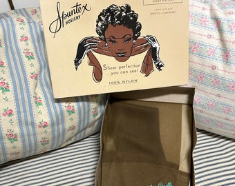 Puede incluir: Caja de medias Spuntex vintage con una ilustración retro de una mujer. La caja beige tiene texto negro y un dibujo de una mujer con guantes. Dentro hay medias de nailon transparentes. El texto de la caja dice "Sheer perfection...you can see!"