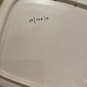 May include: White ceramic plate with a raised rim and a handwritten number "47 | 138 | D" on the bottom.