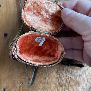 May include: A small, oval-shaped, beaded purse with a gold chain and clasp. The purse is open, revealing a red velvet lining and a label that reads "Kathy's Collectibles".
