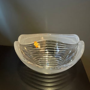 May include: A clear glass bowl with a frosted rim and a wavy, striped design. The bowl is empty and sitting on a black surface.