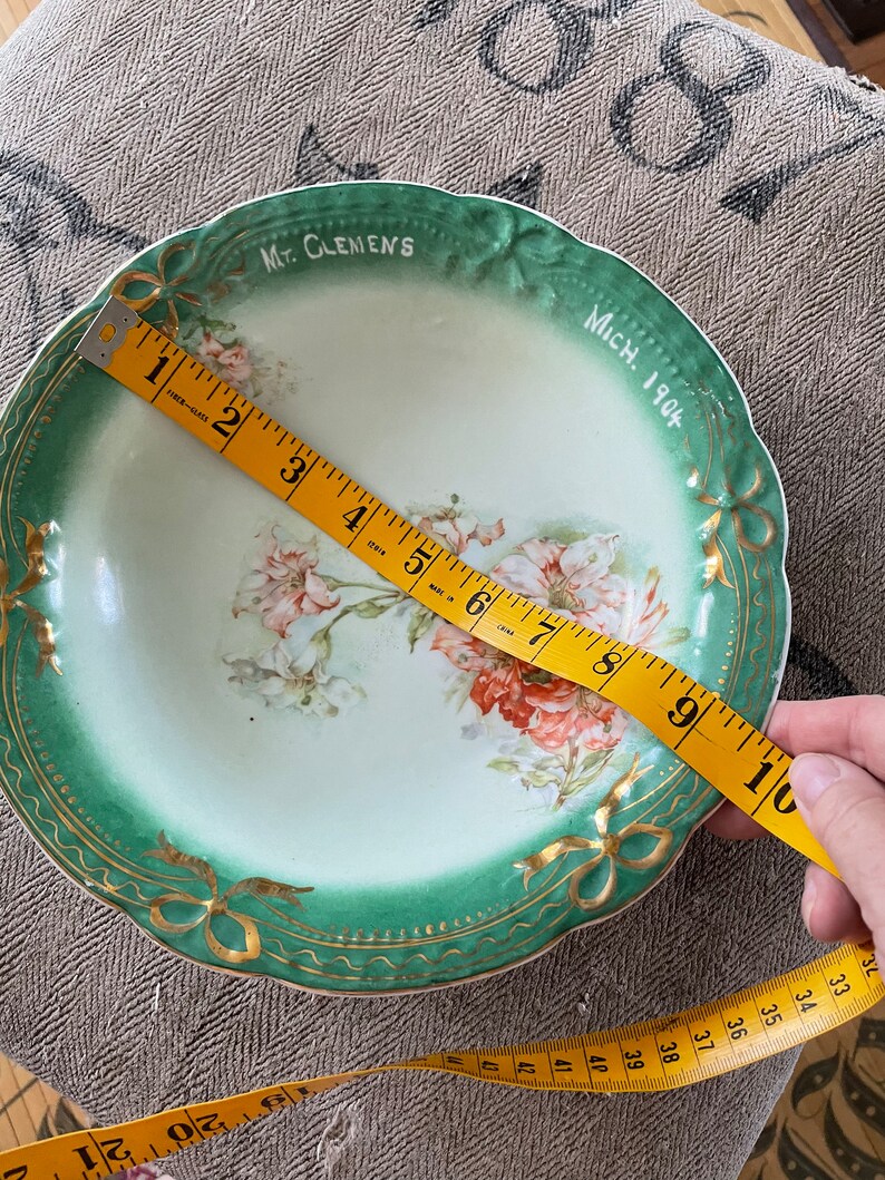 May include: A green and gold ceramic bowl with a floral design and the text "Mt. Clemens Mich. 1904". The bowl is 9 inches in diameter.