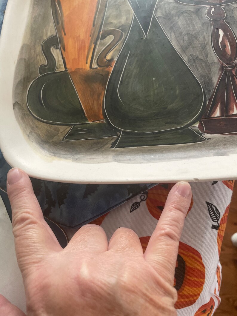 May include: A white ceramic serving tray with a hand-painted design of three vases in shades of brown, green, and black. The vases are stylized and have a modern art aesthetic.