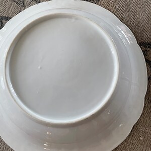 May include: White porcelain plate with a scalloped edge. The plate is plain white with no design.