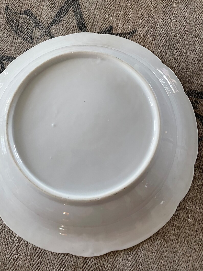 May include: White porcelain plate with a scalloped edge. The plate is plain white with no design.