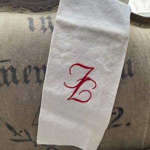 May include: White linen tea towel with a red embroidered letter "Z" in a cursive font.