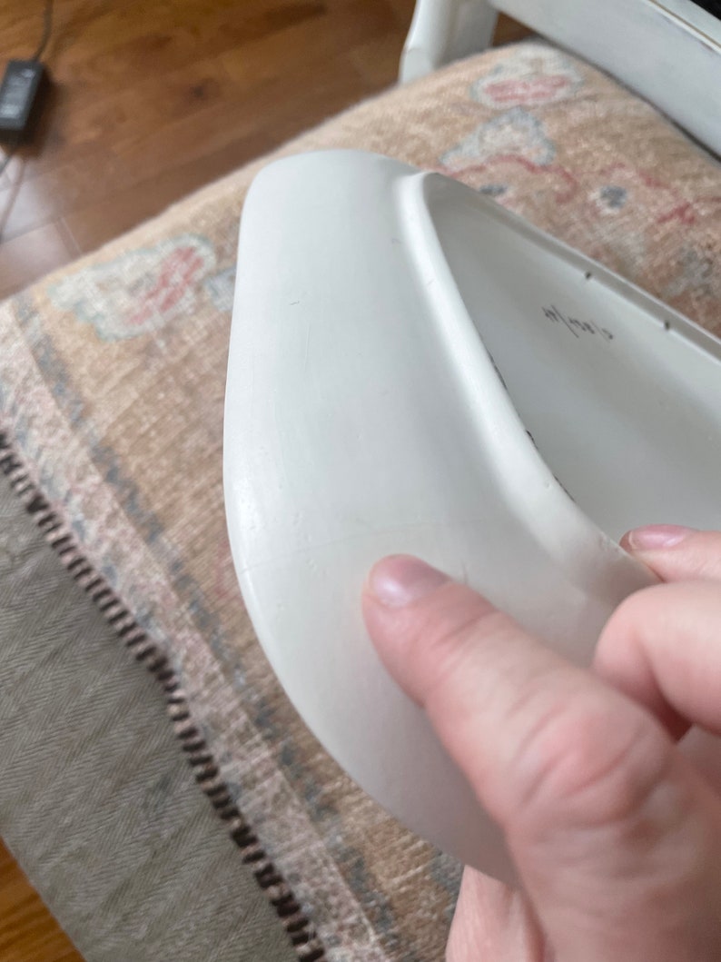 May include: White ceramic plate with a slightly curved edge. The plate has a small scratch on the surface.