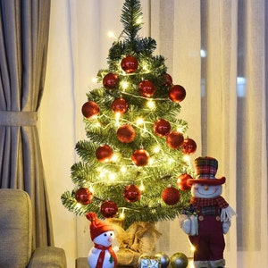 May include: A small artificial Christmas tree decorated with red ornaments and string lights. Two snowman figurines and several decorative silver and gold spheres are placed near the tree, creating a festive holiday display.
