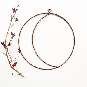 May include: A copper wire moon-shaped plant hanger with a small loop at the top for hanging.