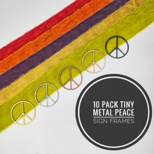 May include: Ten pack of tiny metal peace sign frames in gold, silver, copper, and black. The frames are arranged in a diagonal line on a background of colorful velvet fabric.