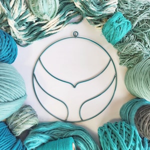 May include: A teal metal hoop with a double-curved design, surrounded by balls of teal yarn.