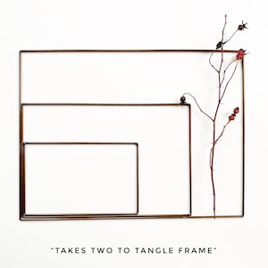 May include: Three overlapping copper wire frames with a dried branch with red berries inside the largest frame. The text "TAKES TWO TO TANGLES FRAME" is below the frames.