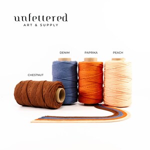 May include: Five spools of cotton cord in different colors: chestnut, denim, paprika, peach. The cord is arranged in a row with the labels for each color above the spools.